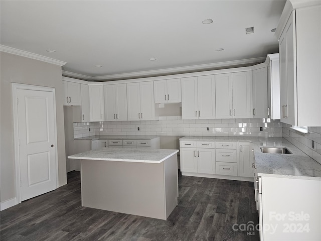 kitchen featuring white cabinets, a center island, crown molding, and dark wood-type flooring