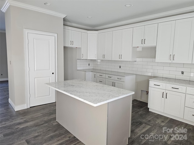 kitchen with backsplash, dark hardwood / wood-style floors, ornamental molding, a kitchen island, and white cabinetry