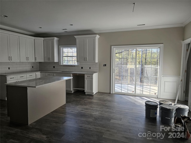 kitchen featuring a center island, dark hardwood / wood-style floors, decorative backsplash, white cabinets, and ornamental molding