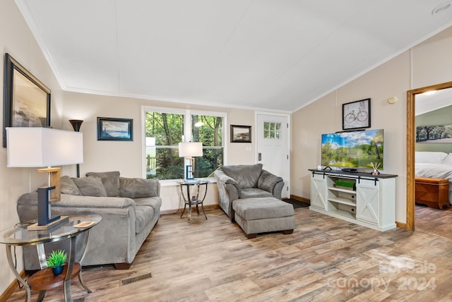 living room featuring light wood-type flooring, ornamental molding, and vaulted ceiling