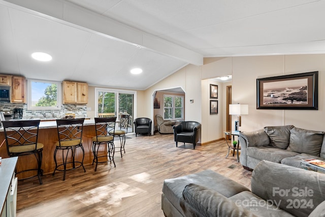 living room featuring vaulted ceiling with beams and light wood-type flooring