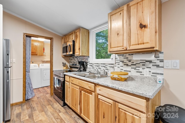 kitchen featuring sink, stainless steel appliances, independent washer and dryer, light hardwood / wood-style floors, and vaulted ceiling