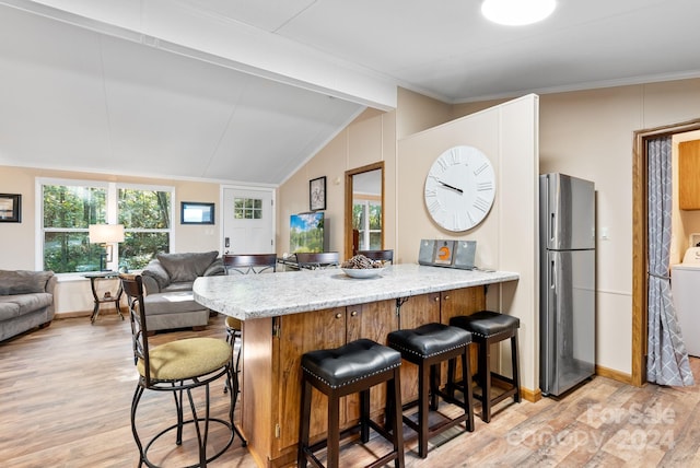 kitchen featuring vaulted ceiling with beams, plenty of natural light, stainless steel fridge, and light hardwood / wood-style floors