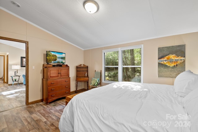 bedroom featuring a textured ceiling, vaulted ceiling, light hardwood / wood-style flooring, and crown molding