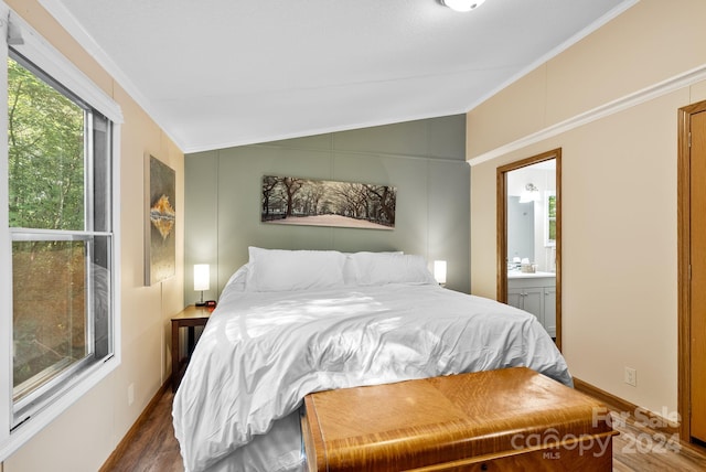 bedroom featuring ensuite bath, crown molding, dark wood-type flooring, and vaulted ceiling