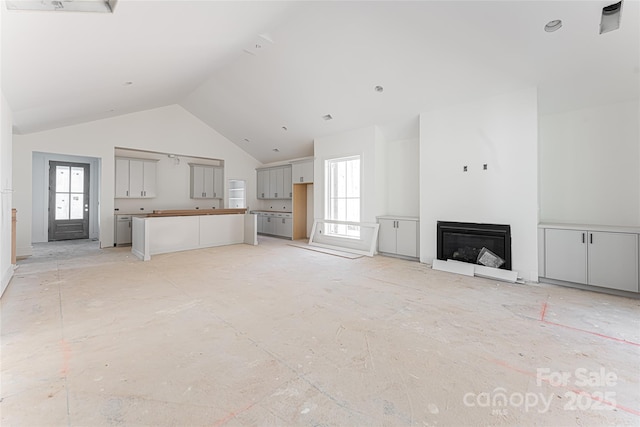 unfurnished living room featuring high vaulted ceiling and a wealth of natural light