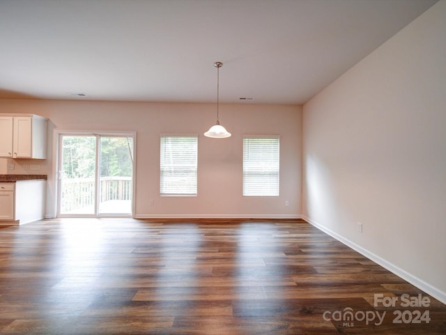 unfurnished dining area featuring dark wood-type flooring and a healthy amount of sunlight