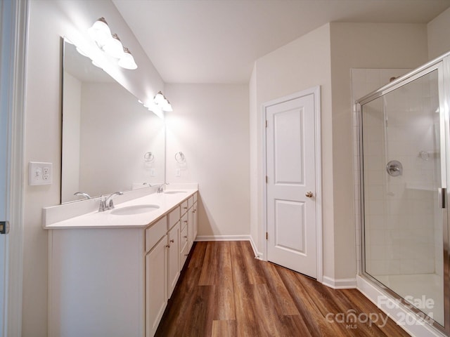 bathroom with hardwood / wood-style floors, a shower with door, and vanity