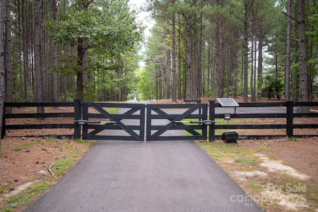 view of gate featuring a wooded view and fence