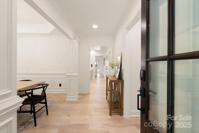 corridor with a decorative wall, recessed lighting, light wood-type flooring, and ornamental molding