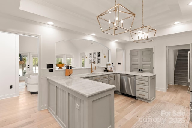 kitchen featuring a sink, light wood-style flooring, a tray ceiling, and stainless steel dishwasher