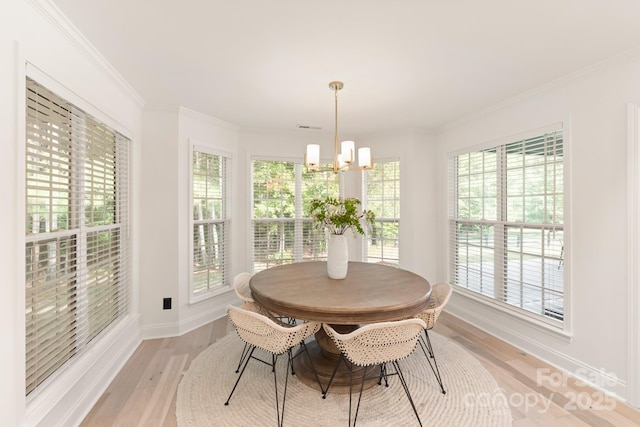 dining space featuring plenty of natural light, ornamental molding, light wood-type flooring, and a chandelier