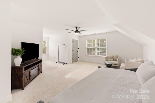 bedroom featuring multiple windows, a ceiling fan, baseboards, and light carpet