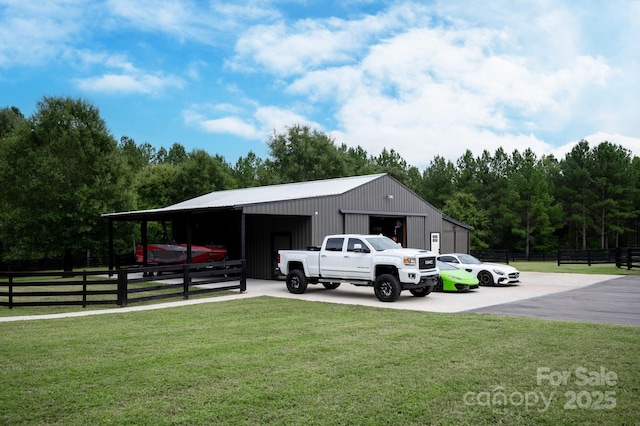 exterior space featuring a detached garage, fence, and a pole building