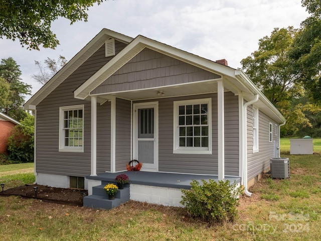 bungalow with a porch, a front lawn, and central air condition unit