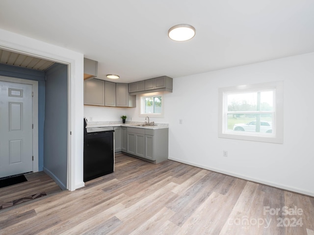 kitchen with gray cabinets, light wood-type flooring, black range oven, and sink