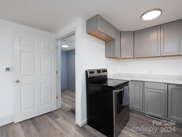 kitchen with gray cabinetry, light hardwood / wood-style flooring, and electric range