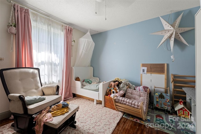 bedroom featuring a textured ceiling, hardwood / wood-style flooring, and multiple windows