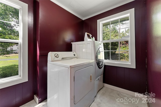 clothes washing area featuring crown molding, washing machine and dryer, and wooden walls