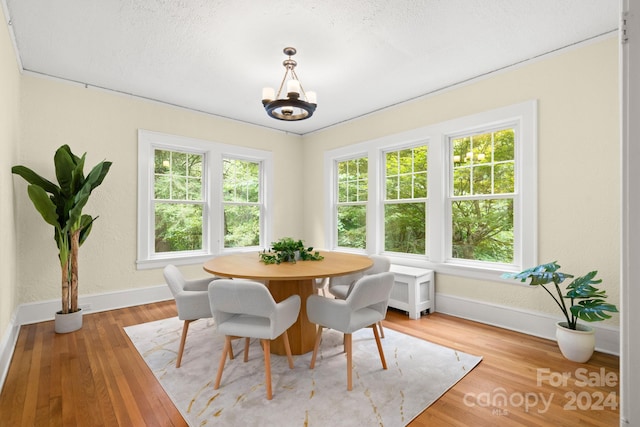 dining area with light wood-type flooring and an inviting chandelier