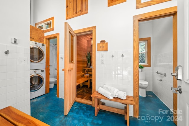 laundry area with tile walls and stacked washer and dryer