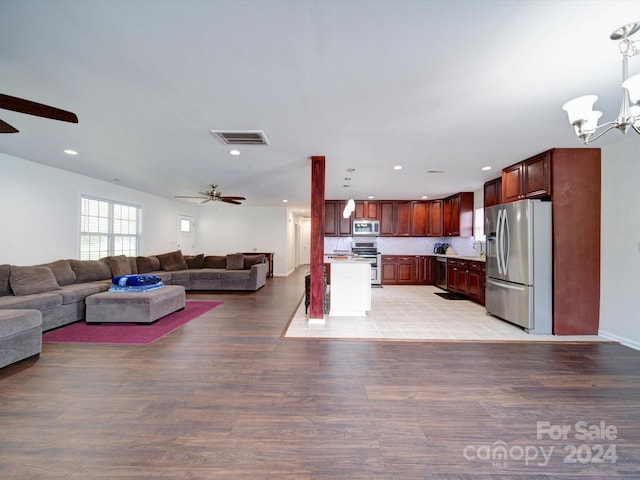 kitchen featuring ceiling fan with notable chandelier, decorative light fixtures, tasteful backsplash, stainless steel appliances, and light wood-type flooring