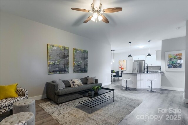 living room featuring ceiling fan, sink, and light hardwood / wood-style floors