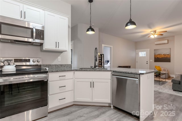 kitchen with white cabinetry, stainless steel appliances, sink, and an AC wall unit