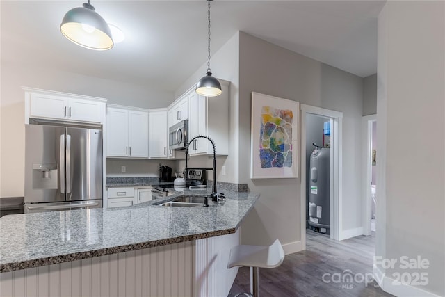 kitchen featuring dark stone countertops, appliances with stainless steel finishes, kitchen peninsula, water heater, and white cabinets