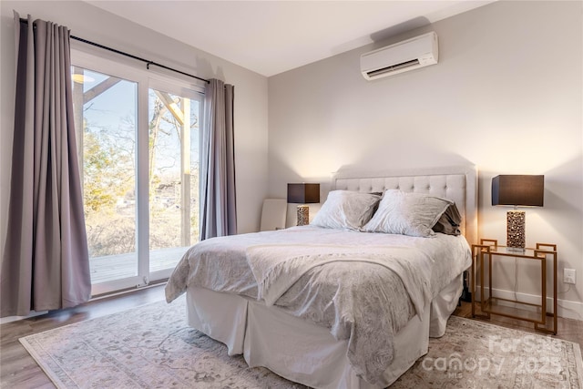 bedroom featuring hardwood / wood-style flooring, a wall mounted air conditioner, and access to outside