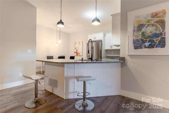 bar featuring pendant lighting, white cabinetry, stainless steel fridge, and sink