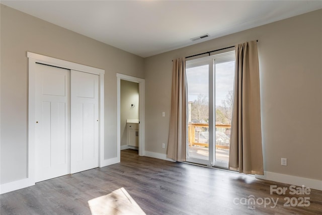 unfurnished bedroom with ensuite bath, access to exterior, a closet, and light hardwood / wood-style flooring