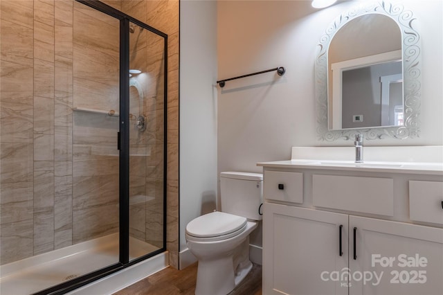 bathroom with walk in shower, hardwood / wood-style floors, vanity, and toilet