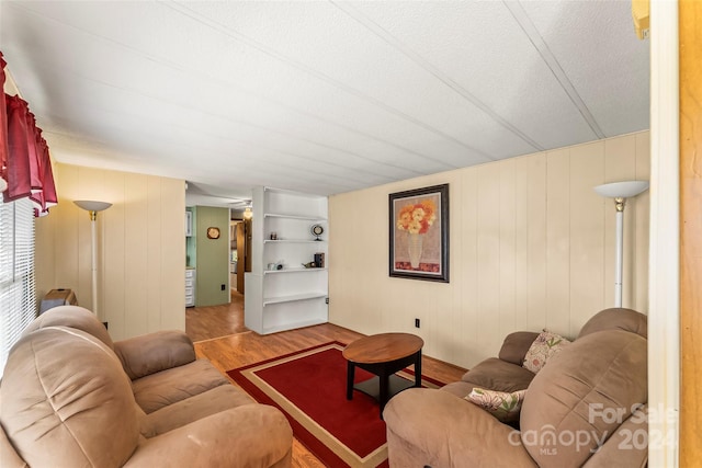 living room featuring a textured ceiling, hardwood / wood-style flooring, and wooden walls