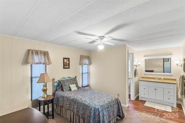 bedroom with ceiling fan, hardwood / wood-style flooring, a textured ceiling, and sink