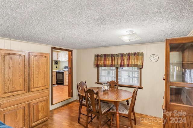 dining area with a textured ceiling and light hardwood / wood-style floors