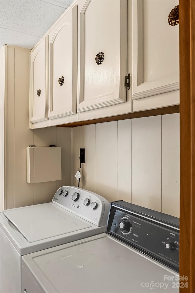 laundry room featuring washing machine and clothes dryer and cabinets