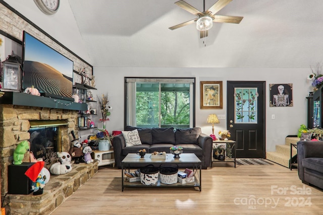 living room featuring a textured ceiling, vaulted ceiling, a fireplace, light hardwood / wood-style flooring, and ceiling fan