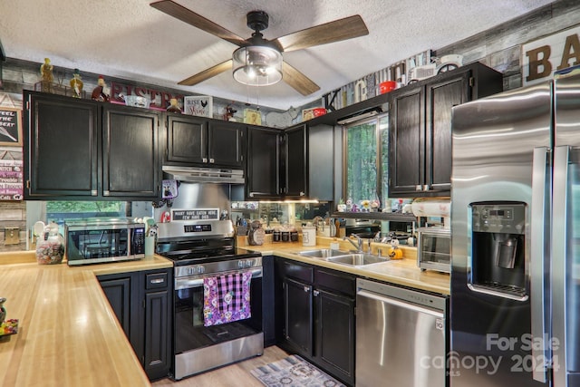 kitchen featuring butcher block countertops, ceiling fan, stainless steel appliances, and a textured ceiling