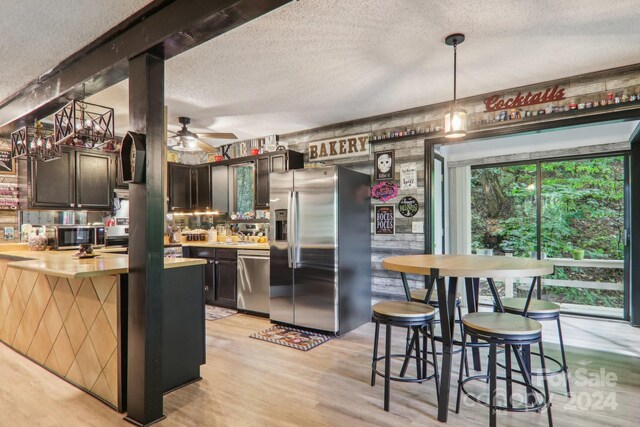 kitchen with appliances with stainless steel finishes, a textured ceiling, and a wealth of natural light