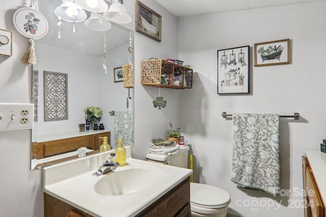 bathroom with vanity, toilet, and a textured ceiling