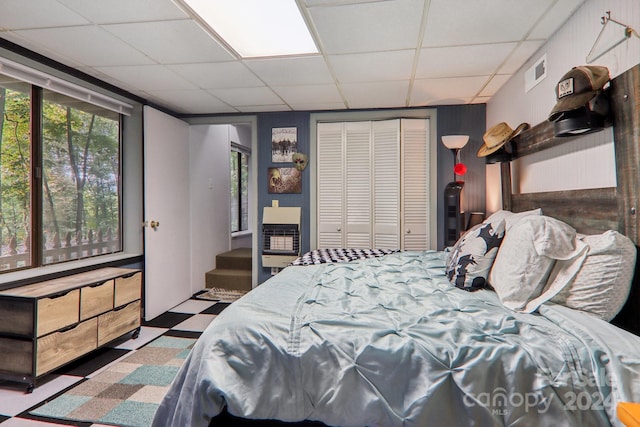 bedroom featuring a drop ceiling and a closet