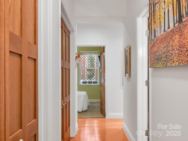 hall featuring light wood finished floors and baseboards