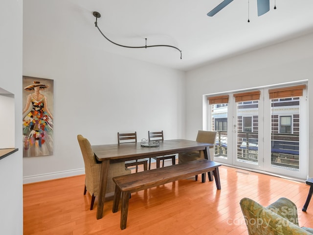 dining space featuring baseboards, a ceiling fan, and light wood-style floors