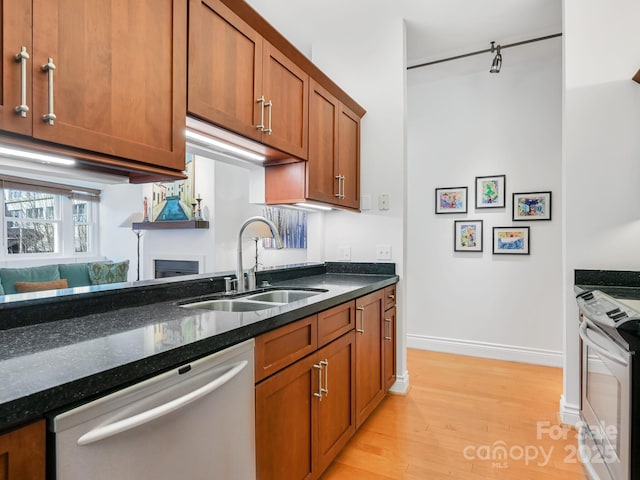 kitchen featuring a sink, open floor plan, stainless steel dishwasher, range, and dark stone counters