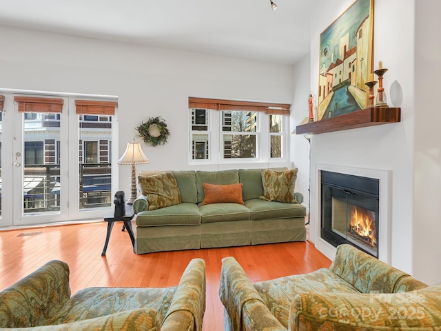 living room with wood finished floors, a glass covered fireplace, and visible vents