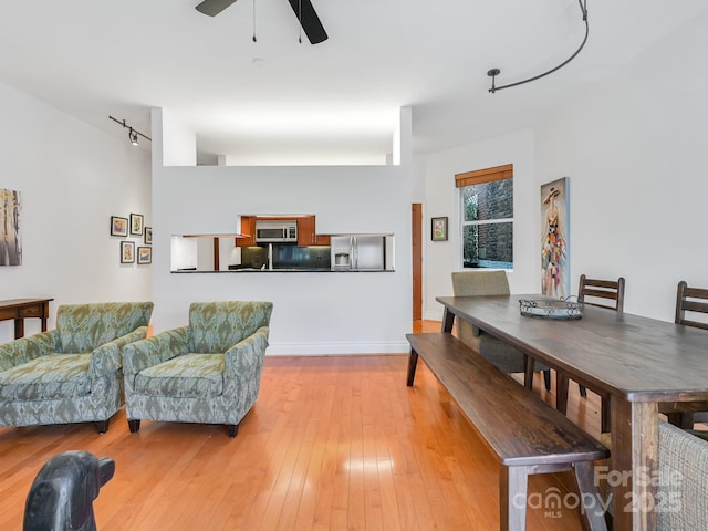 interior space with a ceiling fan, baseboards, and light wood finished floors