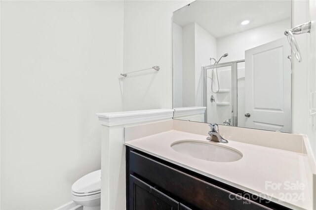 bathroom featuring vanity, toilet, and an enclosed shower