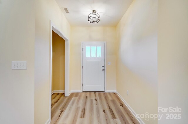 doorway featuring visible vents, light wood-type flooring, and baseboards