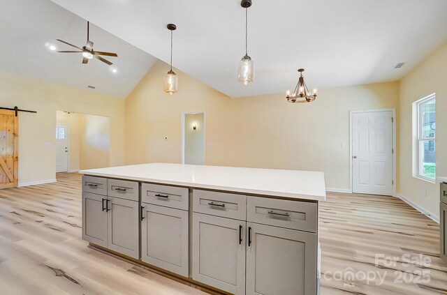 kitchen featuring pendant lighting, a barn door, gray cabinetry, and light wood-style flooring